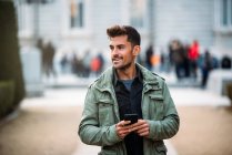Young man on the mobile phone and walking in madrid during winter — Stock Photo