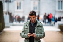 Young man on the mobile phone and walking in madrid during winter — Stock Photo