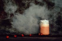 Fumo bianco sottile che si diffonde su un tavolo con barattolo di caffè fresco e spezie aromatiche — Foto stock