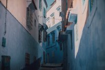 Calle estrecha con edificios antiguos de piedra caliza azul y blanco, Chefchaouen, Marruecos - foto de stock