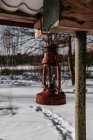 Linterna roja envejecida que cuelga de la construcción cerca del prado de nieve en Vilna, Lituania - foto de stock