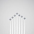 Grupo de chorros que emiten humo de color mientras vuelan sobre el fondo del cielo azul claro - foto de stock