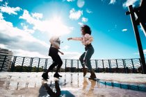 Дві щасливі африканські друзі танцюють на вулиці на заході сонця — стокове фото