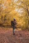 Senhora de chapéu e casaco de esqui com mochila e bengala no caminho entre a floresta de outono em Isoba, Castela e Leão, Espanha — Fotografia de Stock