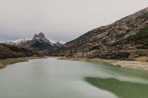 Incredibile vista della superficie dell'acqua tra alte montagne con alberi sul cielo nuvoloso nei Pirenei — Foto stock
