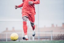 Jogador de futebol africano com roupa vermelha jogando futebol. — Fotografia de Stock