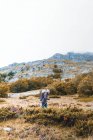 Вид сбоку на человека с рюкзаком на лужайке, облачное небо и вид на горы с лесом в Исобе, Кастиле и Леоне, Испания — стоковое фото