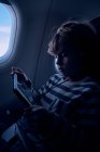 Милий хлопчик дивиться фільм на планшеті в літаку — стокове фото