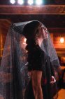Вид сбоку на привлекательную женщину в вуали и платье на сцене, освещенной огнями — стоковое фото