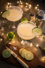 Glasses of margarita cocktail on illuminated table with ingredient — Stock Photo