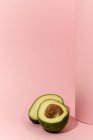 Avocat frais coupé en deux sur fond rose — Photo de stock