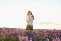 Молодая женщина стоит между фиолетовым лавандовым полем — стоковое фото