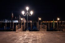Luminoso lampione in piedi sul marciapiede vicino al canale nella splendida notte nella maestosa Venezia — Foto stock