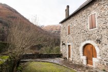 Cantiere con erba verde tra roccia grigia vecchia casa con porte rosse in Pirenei — Foto stock