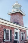 Старый маяк у моря в солнечную погоду — стоковое фото