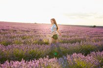 Jovem caminhando entre campo de lavanda violeta — Fotografia de Stock
