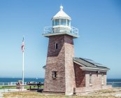 Aged brick lighthouse on shore near water surface and blue sky in San Francisco, USA — Stock Photo
