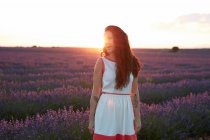 Junge Frau steht im Gegenlicht zwischen violettem Lavendelfeld — Stockfoto