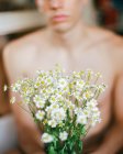 Immagine ritagliata di giovane ragazzo senza maglietta con fresche fioriture bianche nelle mani — Foto stock