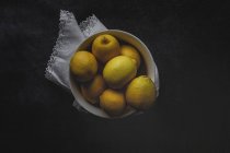 Limoni freschi in ciotola bianca su fondo scuro — Foto stock