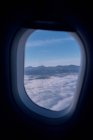 View of white clouds and mountain ridge from window of modern aircraft — Stock Photo