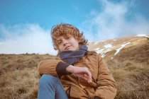 Симпатичний хлопчик сидить на пагорбі біля струмка — стокове фото