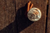 Ароматические палочки корицы возле банки вкусного кофе со сливками на пилораме — стоковое фото