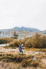 Побоковий вид людини з рюкзаком на лузі, хмарне небо та гори з лісом в Ісобі, Кастилії та Леоні, Іспанія. — стокове фото