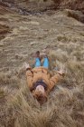 Niño acostado en hierba seca cerca de arroyo - foto de stock