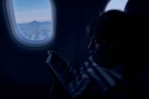 Bonito menino assistindo filme no tablet no avião — Fotografia de Stock