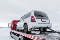Машина на евакуаторі на сніговій дорозі — стокове фото
