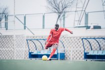 Giocatore di calcio africano con vestito rosso giocare a calcio. — Foto stock