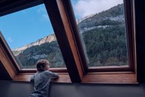 Хлопчик дивиться на гору через вікно — стокове фото