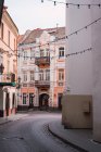 Garlands with light bulbs hanging between beautiful buildings on narrow street of old city — Stock Photo