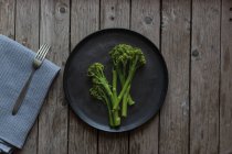 From above shot of fork and napkin lying near plate with healthy green broccoli — Stock Photo