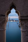 Beautiful view of magnificent building and calm water of channel behind ornamental stone arch in cloudy evening in Venice — Stock Photo