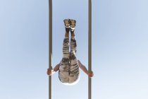 From below woman in sportswear doing exercises on parallel bars and blue sky — Stock Photo