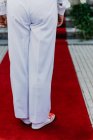 Person in white cloth and gym shoes jumping on red carpet — Stock Photo