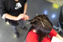 Estilista envelhecido fazendo penteado para atraente jovem senhora no salão de cabeleireiro — Fotografia de Stock