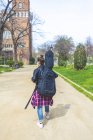 Вид спереду молода хіпстерка, що гуляє в парку в сонячний день, несучи гітару на спині — стокове фото