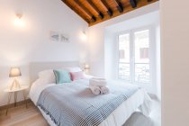 Confortevole stanza luminosa con grande letto e lampade vicino alla finestra nella casa moderna — Foto stock