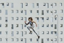 Side view of athletic woman levitating near building in sunny weather — Stock Photo