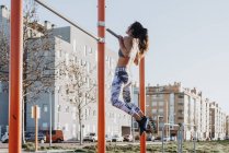 Frau trainiert auf der Straße am Stufenbarren — Stockfoto