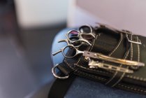 De cima closeup ferramentas de cabeleireiro em saco preto na mesa sobre fundo borrado — Fotografia de Stock