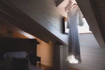 Robe légère séchant près de la fenêtre ouverte dans le grenier sombre de la maison — Photo de stock