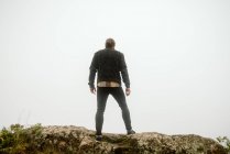 Anonymous man standing on cliff near countryside road — Stock Photo