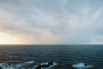 Захватывающий дух вид восходящего солнца на облачном небе над величественным волнистым морем — стоковое фото