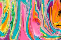 Thick paint of various bright colors flowing down and mixing together — Stock Photo