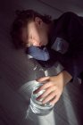 Charming boy with vase of clear water sleeping on floor at home — Stock Photo