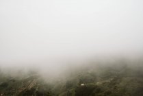 Niebla sobre hermoso terreno montañoso - foto de stock